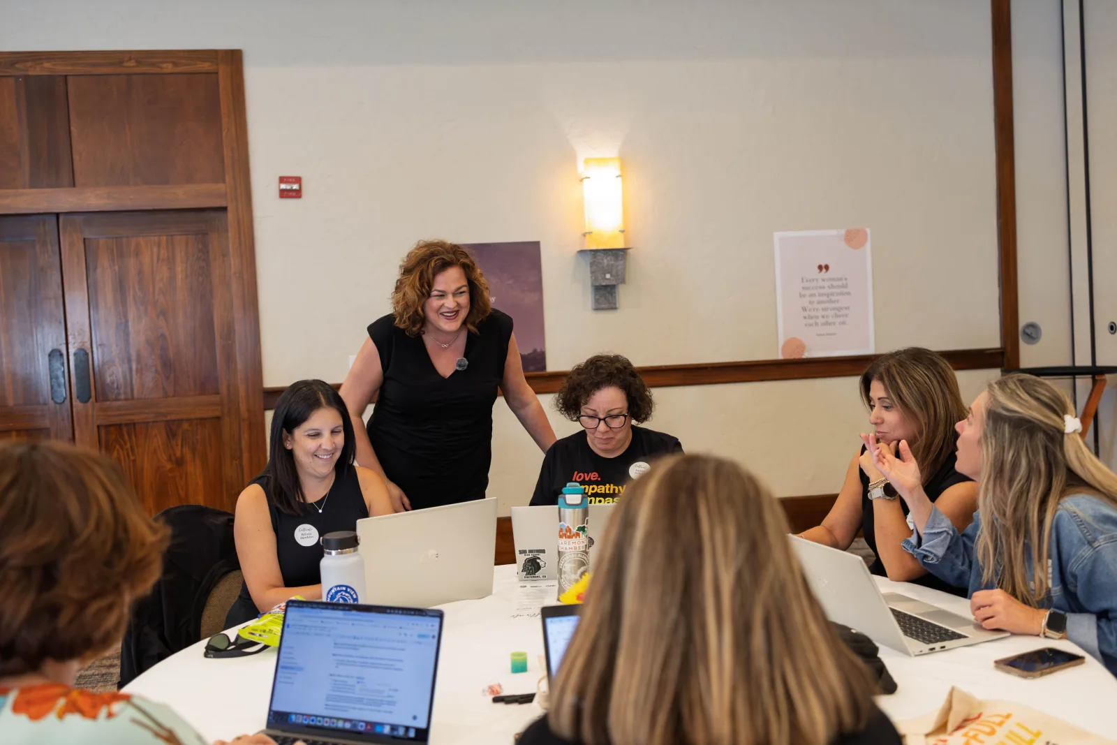 Facilitator laughs with a leadership cohort working on laptops between sessions